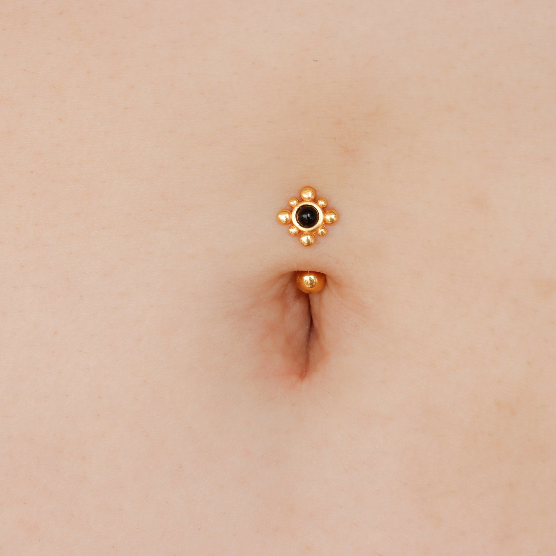 gold and black belly button piercing
