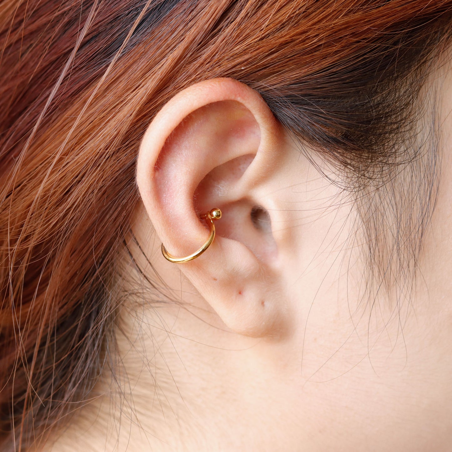 Close-up of an ear wearing a gold hoop earring.