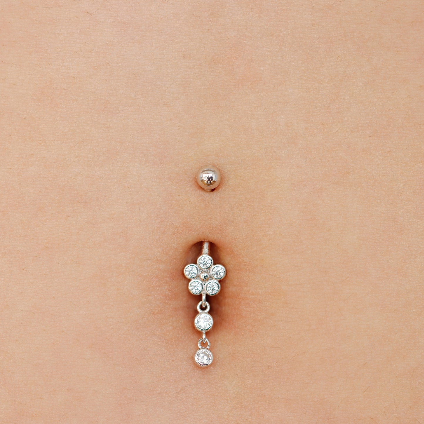 Belly button ring with floral design on a person's belly