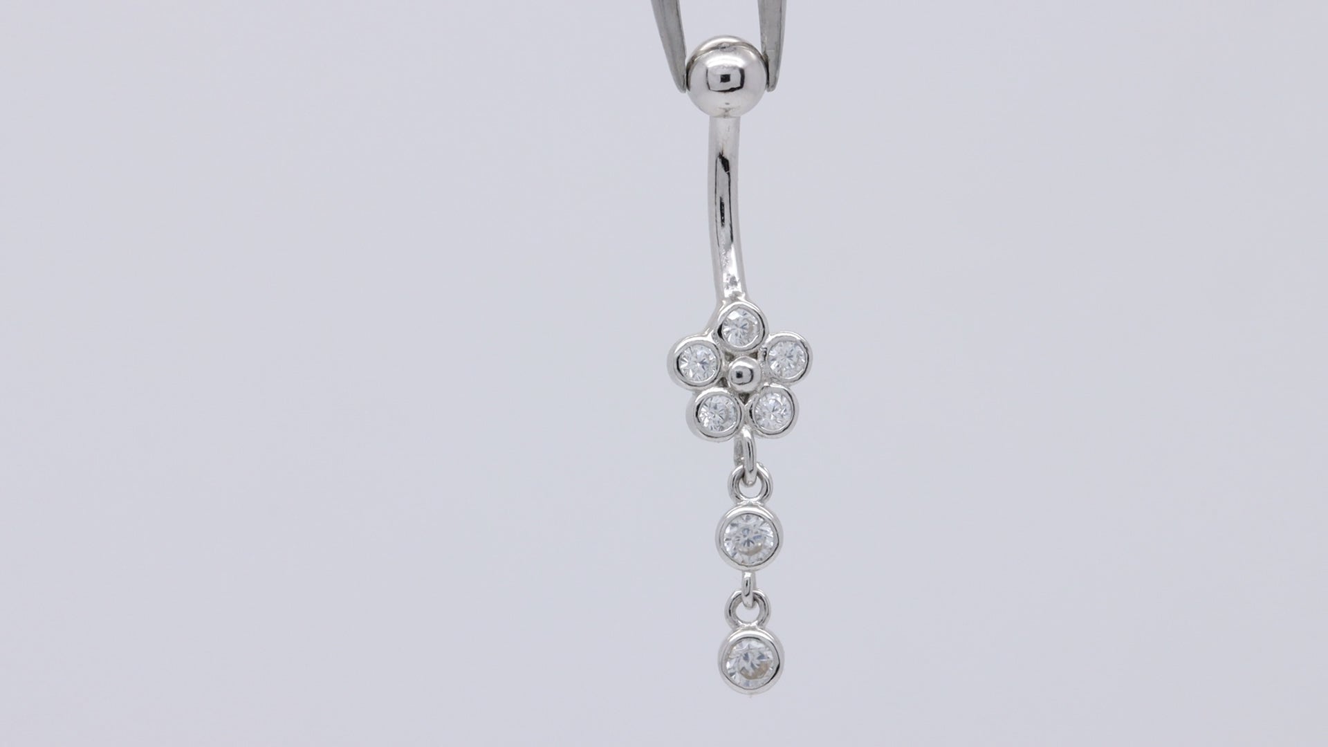 Video demonstration of sterling silver flower dangle belly ring with cubic zirconia charm, showing how it shines and moves