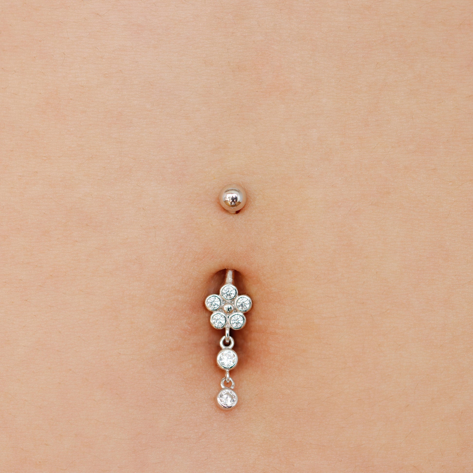 Belly button ring with floral design on a person's belly